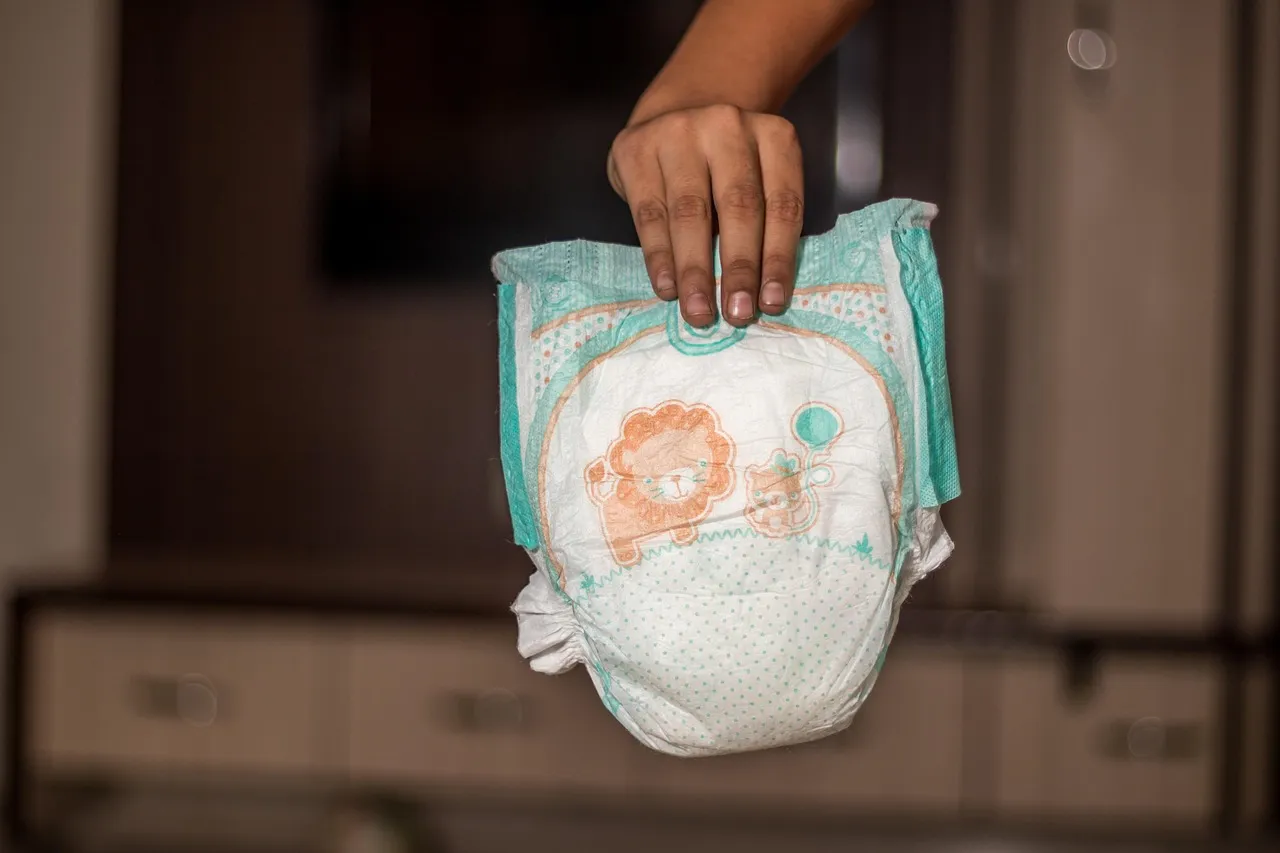 Una mano sosteniendo un pañal desechable para bebé, útil para guías sobre higiene, cambio de pañales o productos básicos para recién nacidos.
